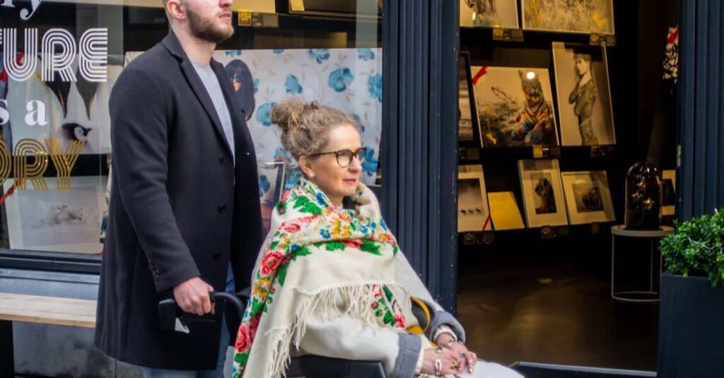Mann begleitet Frau im Rollstuhl vor einer Kunstgalerie – Unterstützung und Inklusion im Alltag