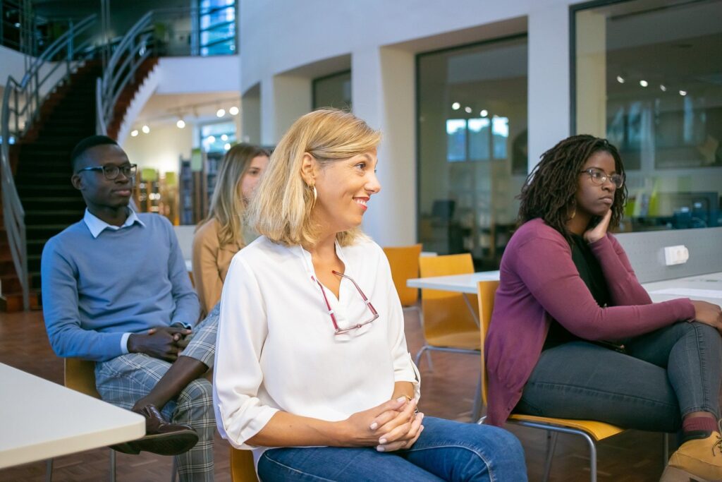 Multikulturelle Gruppe von Erwachsenen nimmt aufmerksam an einem Seminar oder Workshop in moderner Lernumgebung teil